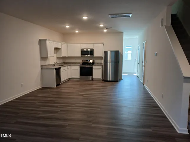 a kitchen with stainless steel appliances wooden floor and a refrigerator