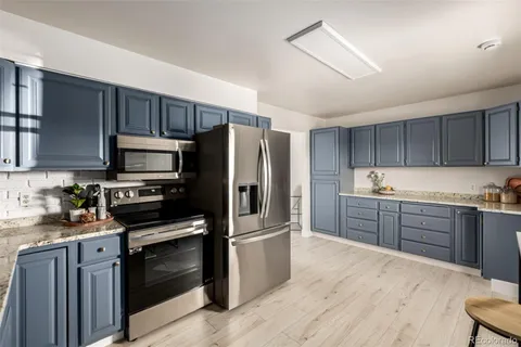 a kitchen with granite countertop a refrigerator stove and microwave