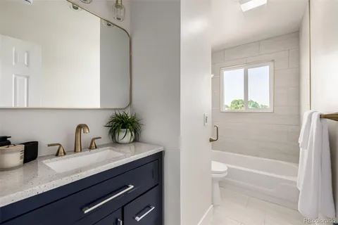 a bathroom with a granite countertop sink a toilet and a bathtub