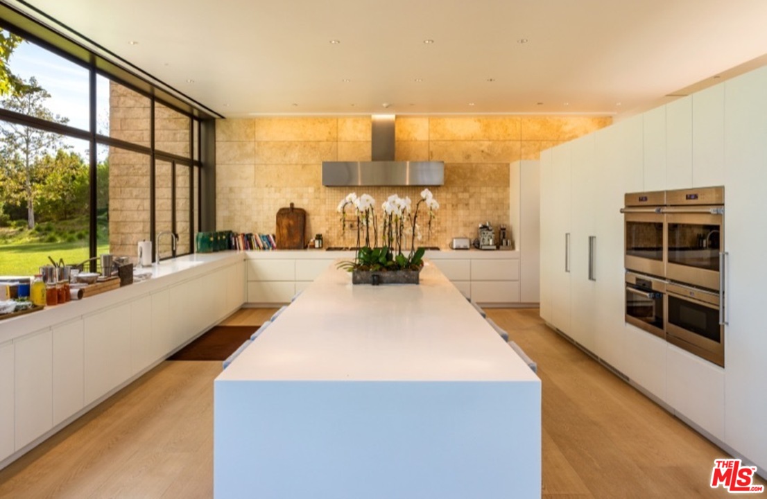 911 Foothill Road Beverly Hills, CA 90210 - Photo 10 of 21 a large white kitchen with wooden floor
