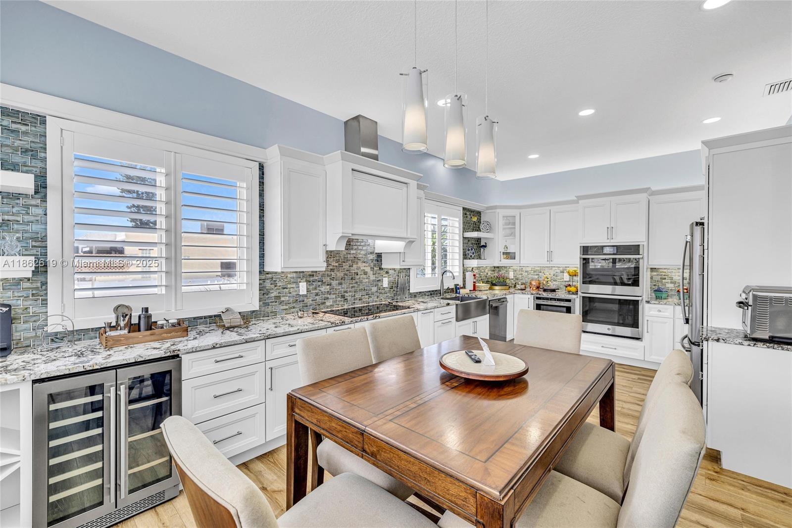 311 North Surf Road, Unit 311 Hollywood, FL 33019 - Photo 5 of 68 a kitchen with a stove a sink a kitchen island with a dining table and chairs