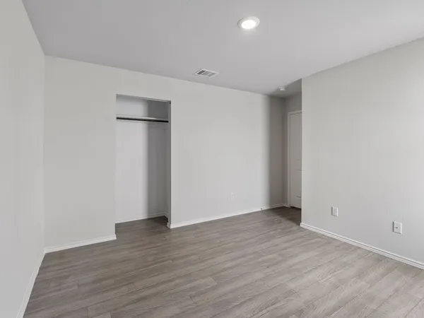 a view of an empty room with wooden floor and closet
