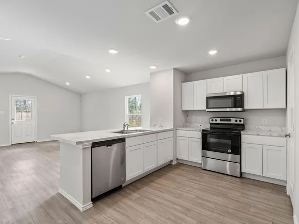 a kitchen with stainless steel appliances granite countertop a stove and white cabinets