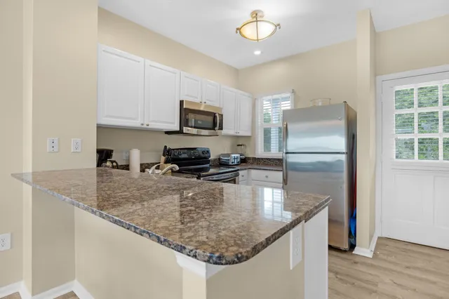 a kitchen with granite countertop a sink stove and microwave