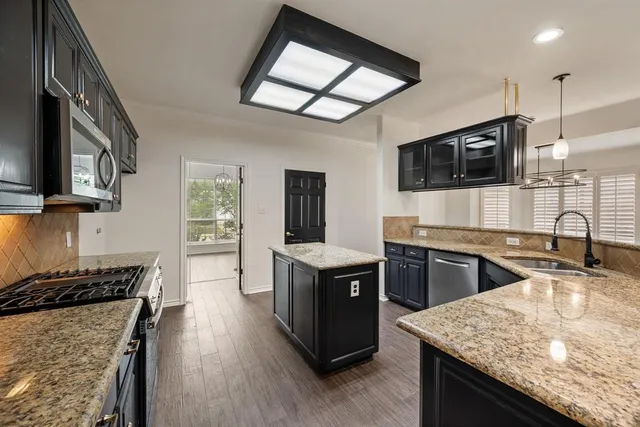a kitchen with stainless steel appliances granite countertop hardwood floor sink stove and granite counter top