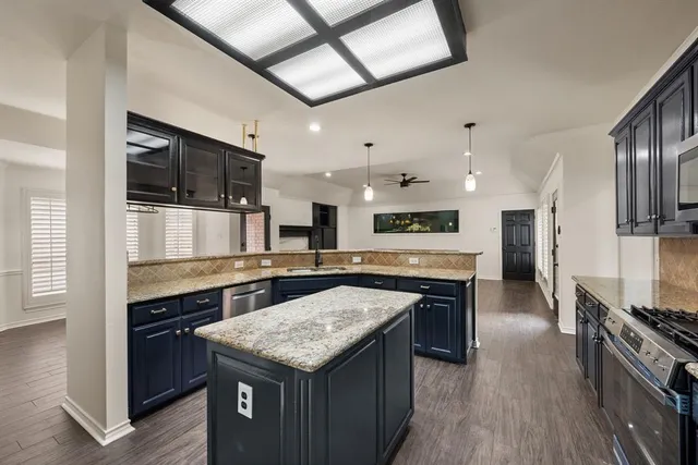 a kitchen with stainless steel appliances granite countertop a stove top oven a sink and a refrigerator