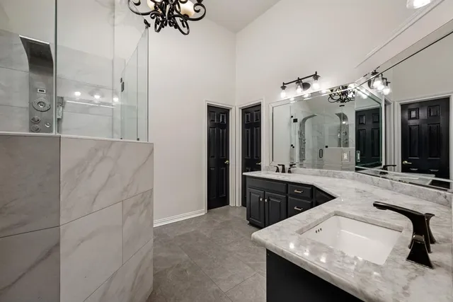 a spacious bathroom with a granite countertop sink a mirror and shower