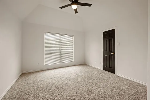 an empty room with chandelier fan and windows