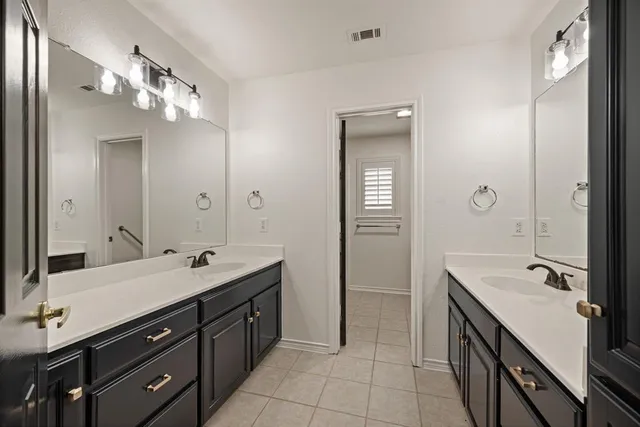 a spacious bathroom with a double vanity sink a large mirror and a shower