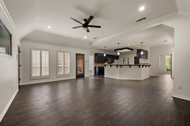 a living room with stainless steel appliances kitchen island hardwood floor and a large window