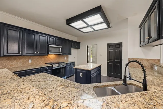 a kitchen with stainless steel appliances kitchen island granite countertop a sink stove and refrigerator
