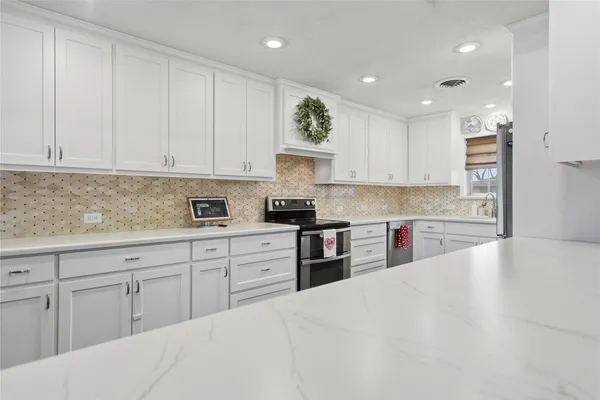 a kitchen with granite countertop white cabinets and stainless steel appliances
