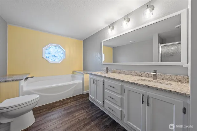 a bathroom with a granite countertop bathtub sink vanity mirror and toilet