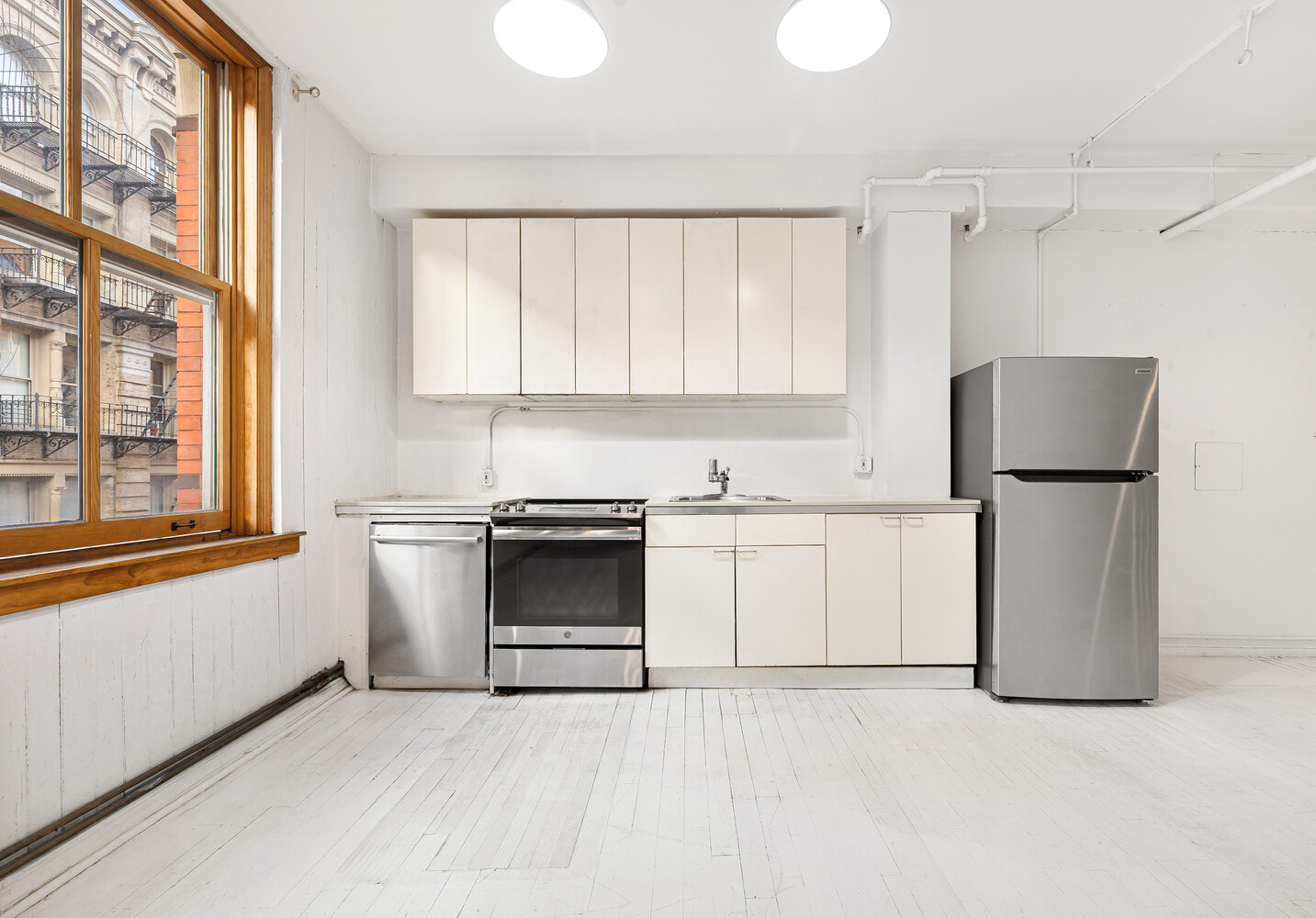 108 Wooster Street, Unit 3A Manhattan, NY 10012 - Photo 4 of 10 a kitchen with white cabinets and white appliances