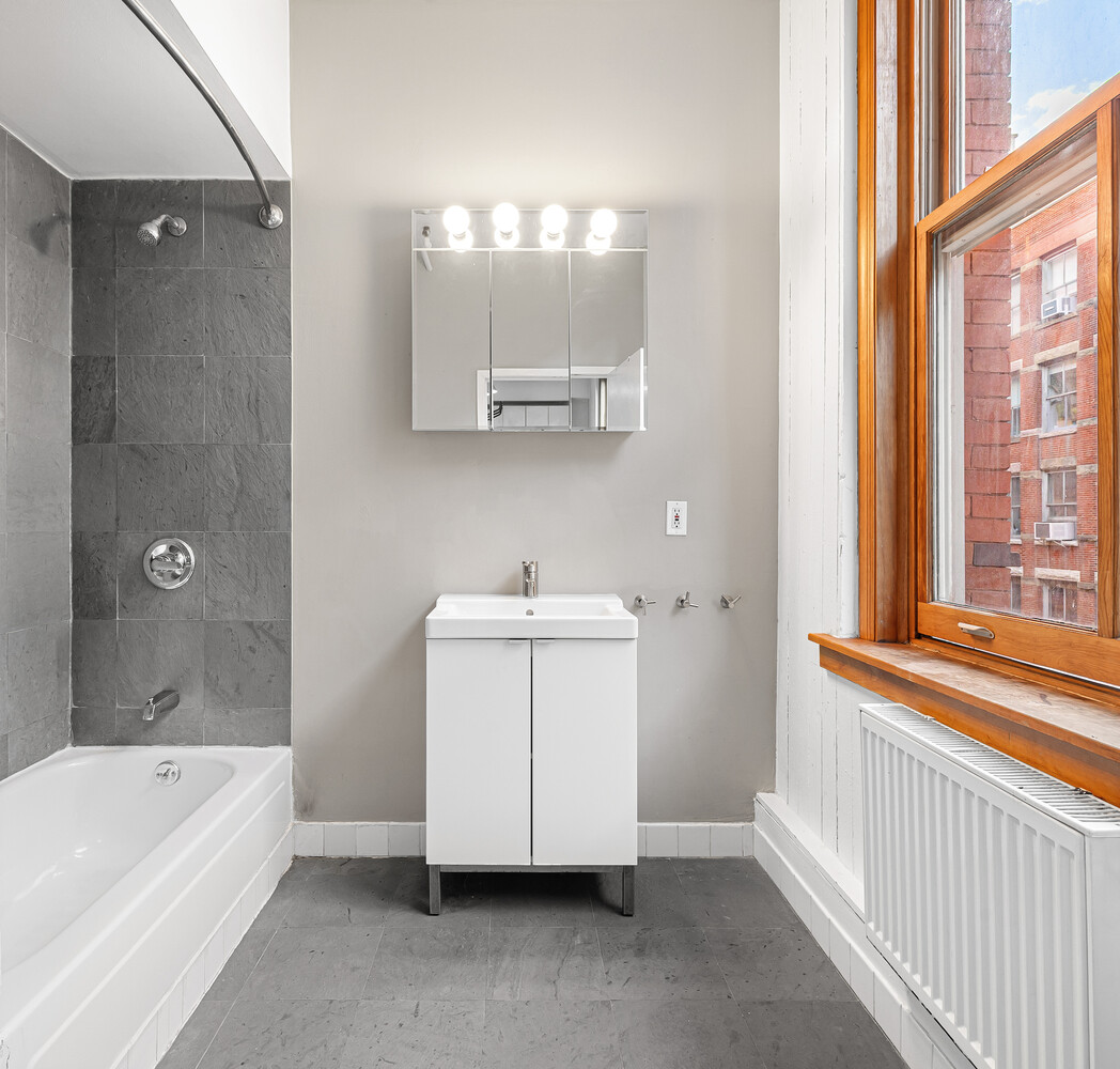108 Wooster Street, Unit 3A Manhattan, NY 10012 - Photo 5 of 10 a bathroom with a tub a sink and a window
