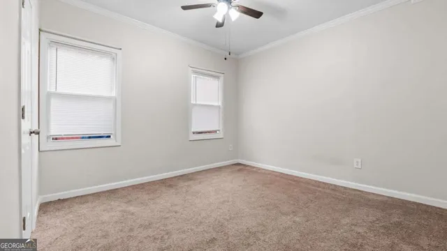 an empty room with a chandelier fan and windows