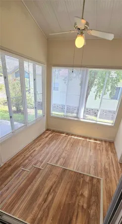a view of an empty room with wooden floor and a window