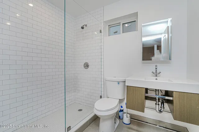 a bathroom with a toilet a sink a mirror and shower