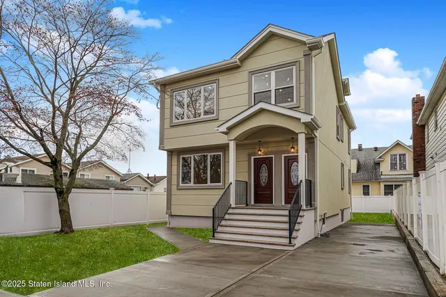 a view of a white house with large windows and a yard