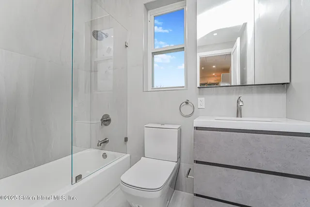 a bathroom with a toilet a sink a mirror a bathtub and shower