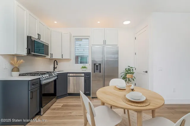 a kitchen with stainless steel appliances granite countertop a kitchen island hardwood floor sink stove dining table and chairs