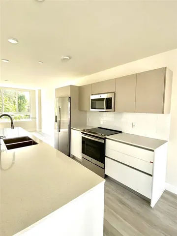 a kitchen with stainless steel appliances a stove a sink and white cabinets