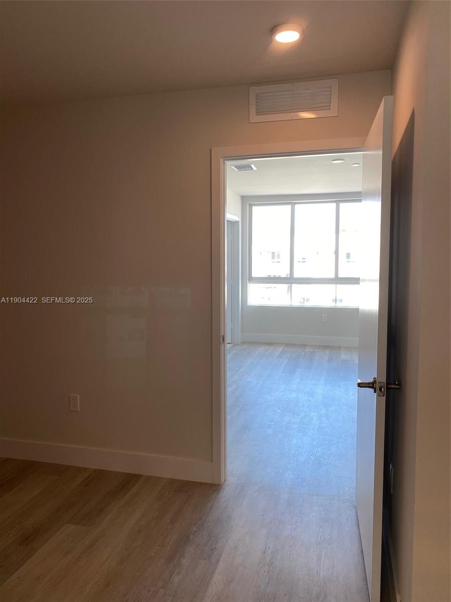 2561 Northeast 193rd Street, Unit 1206 Miami, FL 33180 - Photo 10 of 16 an empty room with wooden floor and windows
