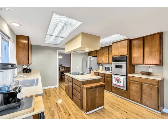 a kitchen with a stove kitchen island wooden cabinets and stainless steel appliances