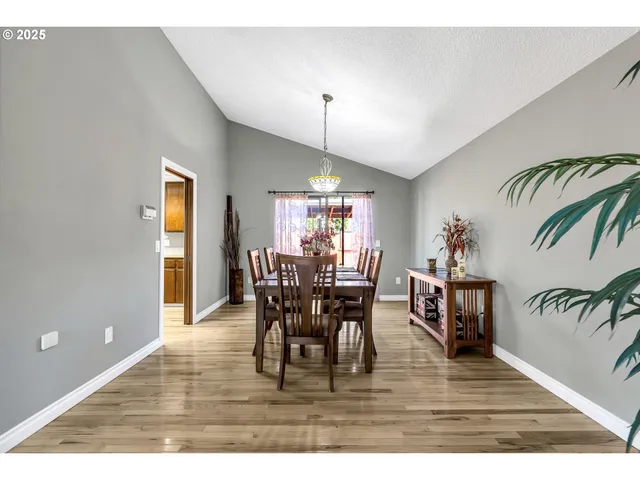 a view of a dining room and livingroom with furniture wooden floor a rug and a chandelier