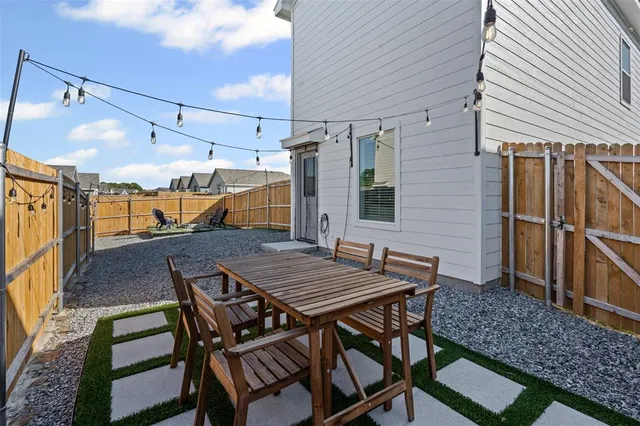 a view of a patio with table and chairs with wooden floor and fence