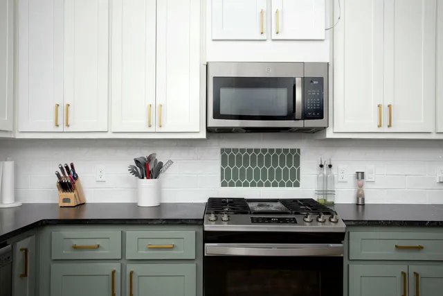 a kitchen with stainless steel appliances granite countertop white cabinets and a stove top oven