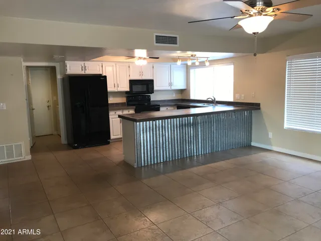 a kitchen with stainless steel appliances kitchen island granite countertop a refrigerator and a sink