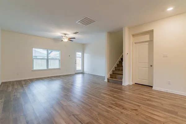 an empty room with wooden floor chandelier and windows