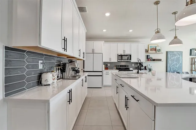 a kitchen with stainless steel appliances kitchen island granite countertop a sink a stove and a refrigerator