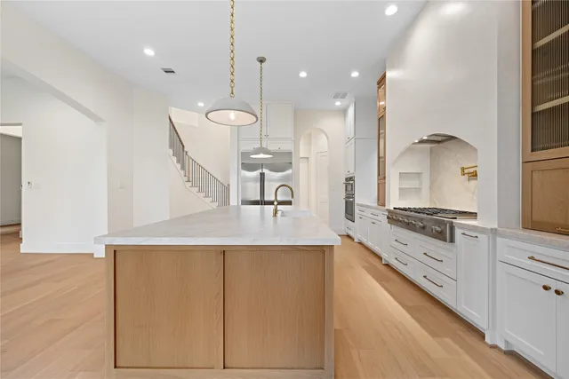 a large kitchen with kitchen island a large counter space a sink a window and stainless steel appliances