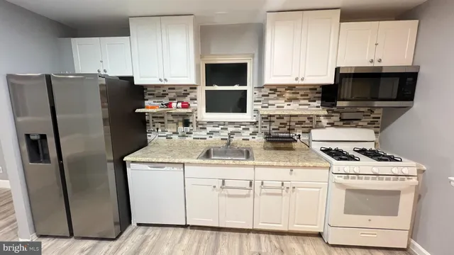 a kitchen with white cabinets sink and stainless steel appliances