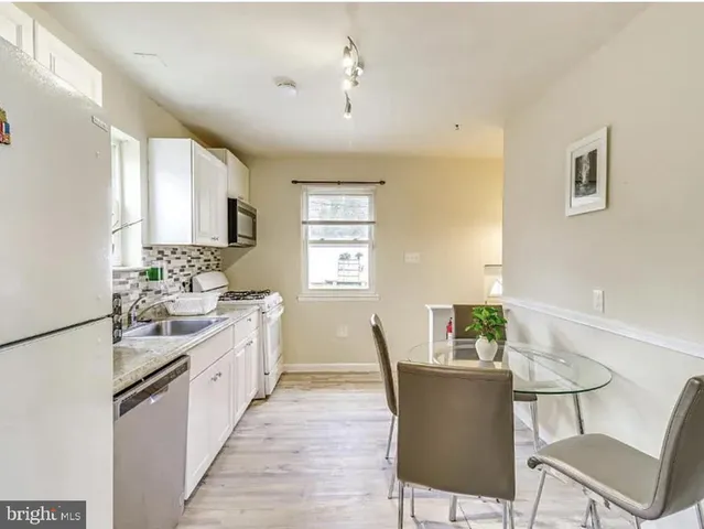 a living room with stainless steel appliances kitchen island granite countertop furniture and a wooden floor