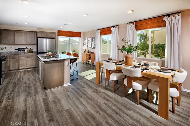 a living room with stainless steel appliances granite countertop furniture wooden floor and a large window