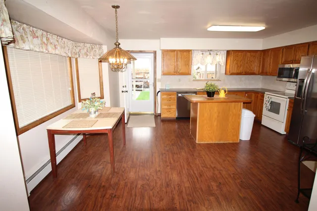 a kitchen with kitchen island granite countertop wooden floors granite counter tops and a view of living room