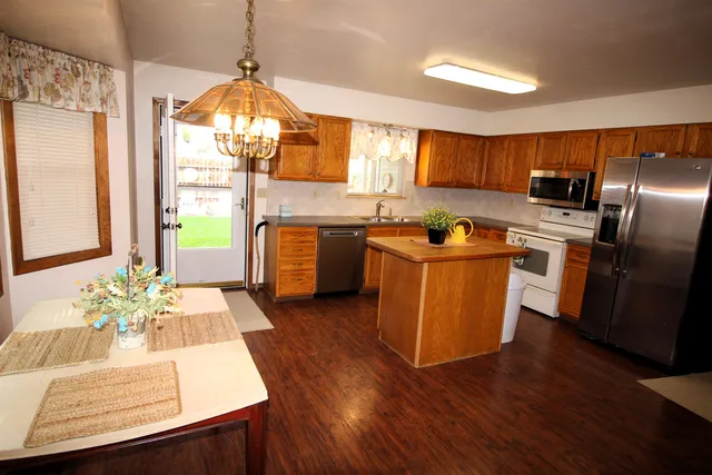 a kitchen with stainless steel appliances granite countertop a refrigerator a sink dishwasher a stove with wooden floor