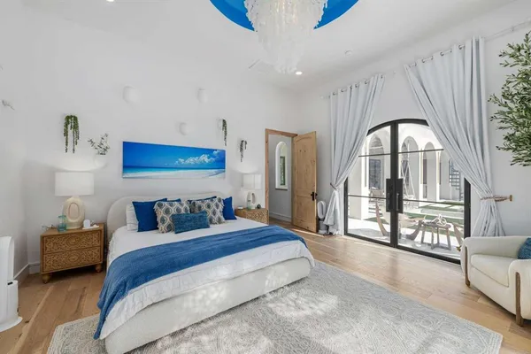 a spacious bedroom with a bed a couch and a potted plant on the dresser