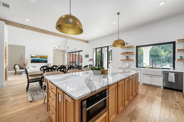 a kitchen with granite countertop a stove a sink a dining table and chairs with wooden floor
