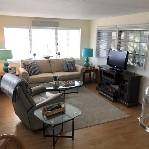 a living room with furniture a flat screen tv and a window