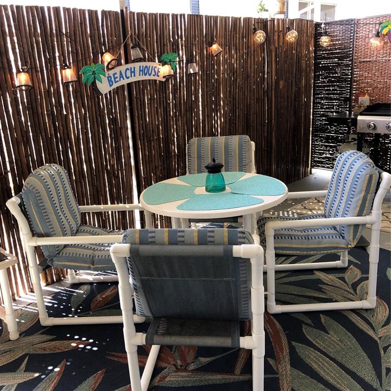 24437 Harbor View Road, Unit 12 Port Charlotte, FL 33980 - Photo 21 of 36 a view of a patio with table and chairs with wooden floor and fence