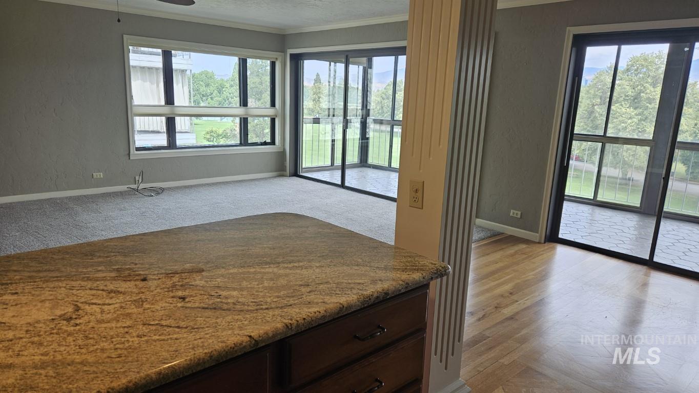3100 Crescent Rim Drive, Unit 308 Boise, ID 83706 - Photo 7 of 34 Kitchen with crown molding, light stone countertops, ceiling fan, dark brown cabinetry, and a textured wall