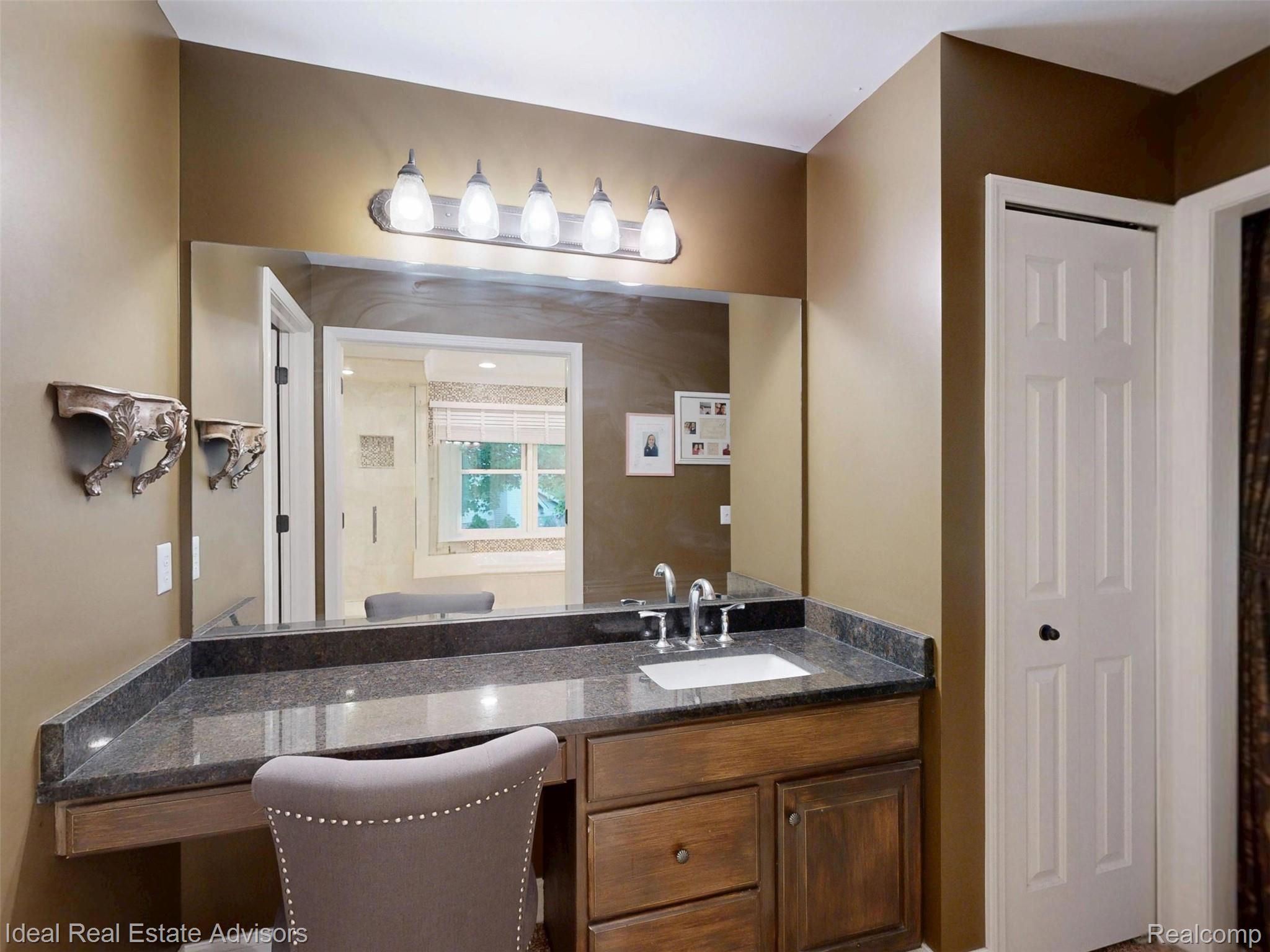 1364 Kentfield Drive Rochester, MI 48307 - Photo 51 of 70 Integrated vanity featuring a dark countertop, an undermount sink with chrome fixtures, and a wood-finish cabinet