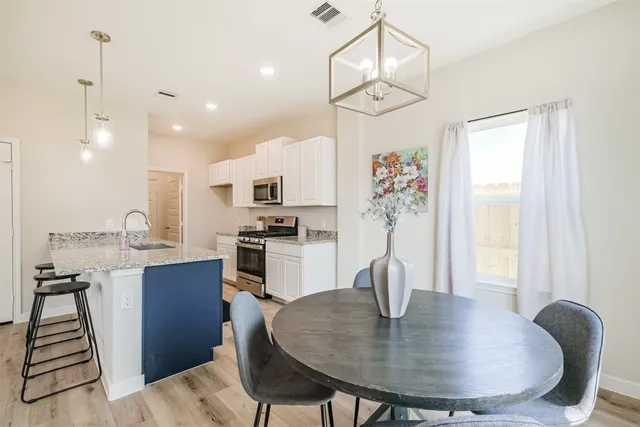 a kitchen with sink refrigerator dining table and chairs