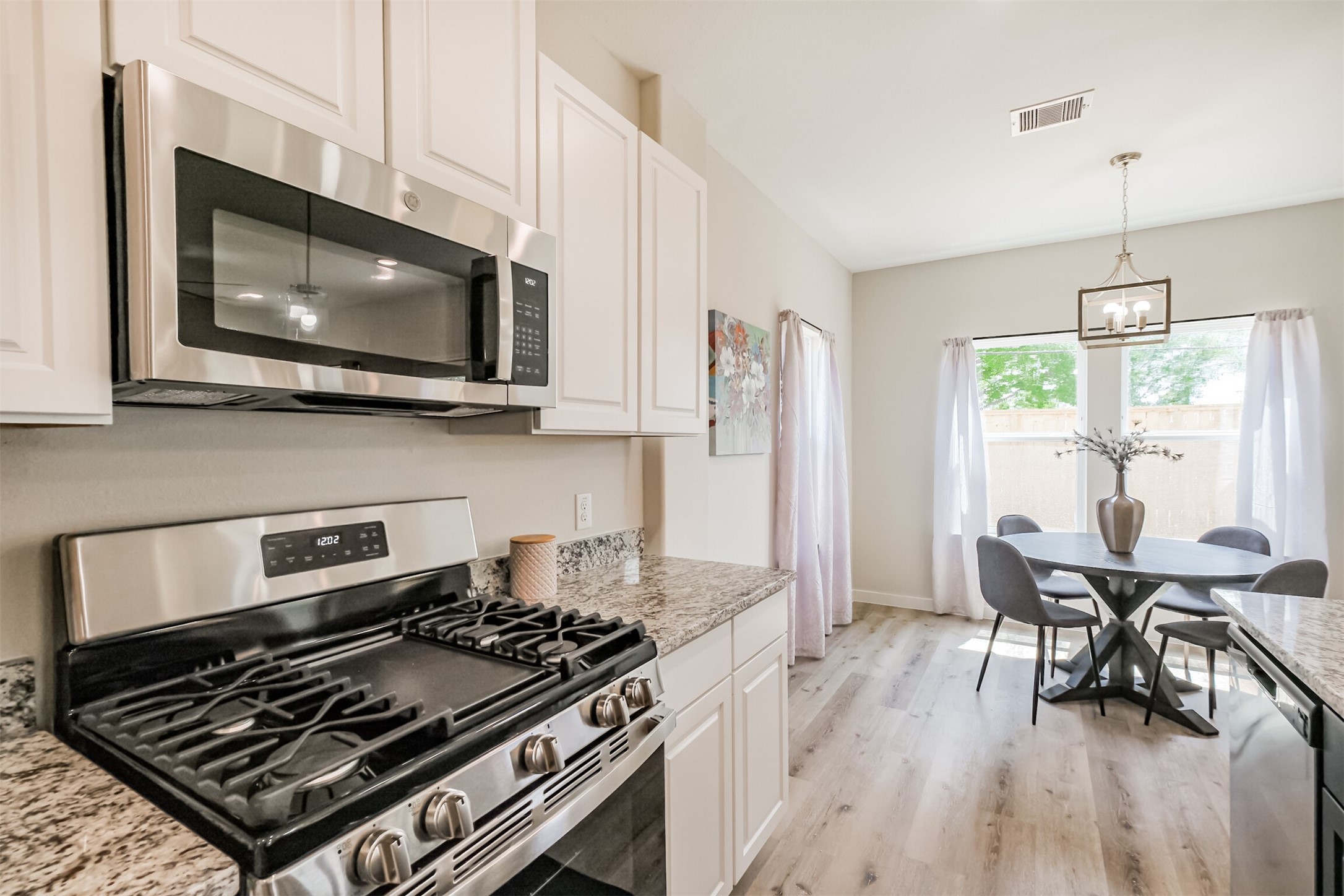 703 Majestic Eagle Court Houston, TX 77090 - Photo 13 of 40 a kitchen with a stove a microwave and wooden floor