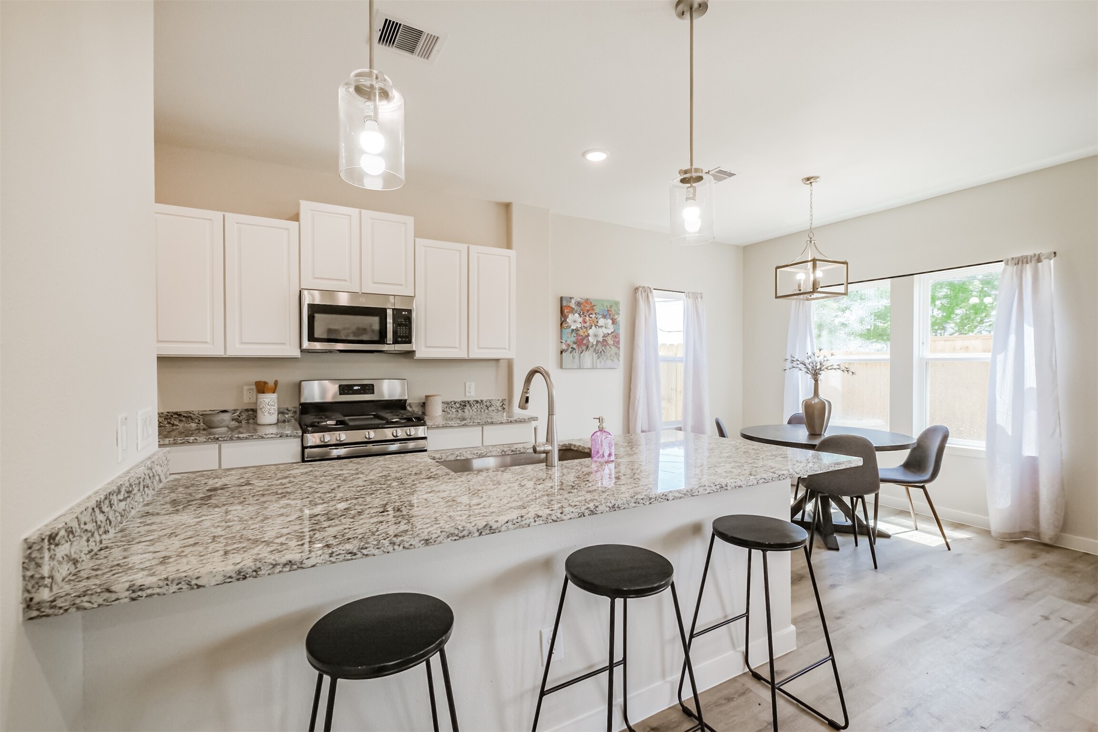 703 Majestic Eagle Court Houston, TX 77090 - Photo 16 of 40 a kitchen with kitchen island granite countertop a dining table chairs sink and microwave