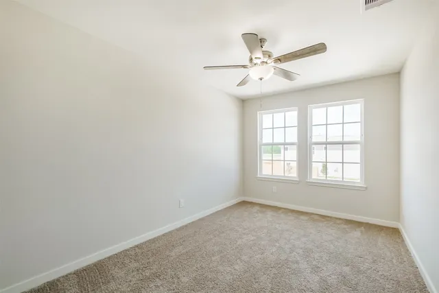 an empty room with a ceiling fan and a window